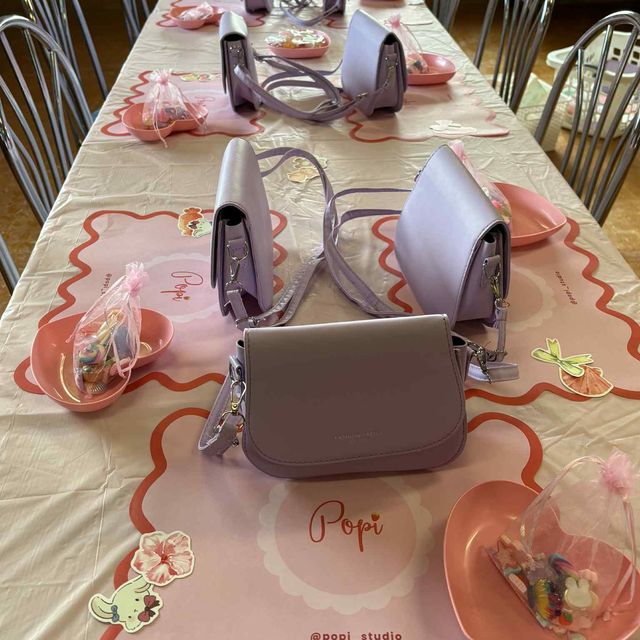 A long party table set with a lilac handbag and a dish of charms at every place on Popi branded mats